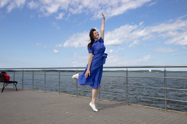 İskelede zıplayan mutlu genç bir kadının portresi. Beyaz kadın deniz kıyısında güneşli bir günün tadını çıkarıyor. Özgürlük kavramı