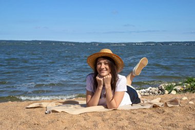 Temiz hava soluyan rahat bir kadının yan görüntüsü, parlak sıcak güneşin altında kumun üzerinde uzanan deniz ve gökyüzü ile fotokopi alanı ile birlikte.