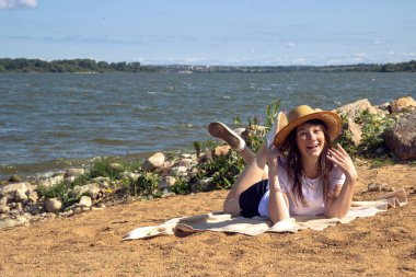 Temiz hava soluyan rahat bir kadının yan görüntüsü, parlak sıcak güneşin altında kumun üzerinde uzanan deniz ve gökyüzü ile fotokopi alanı ile birlikte.