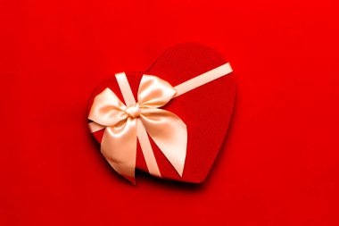 Kırmızı arka planda kırmızı kalp şeklinde hediye kutusu