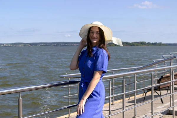 İskelede saman şapkalı, zarif elbiseli genç bir kadın harika bir manzaranın tadını çıkarıyor..