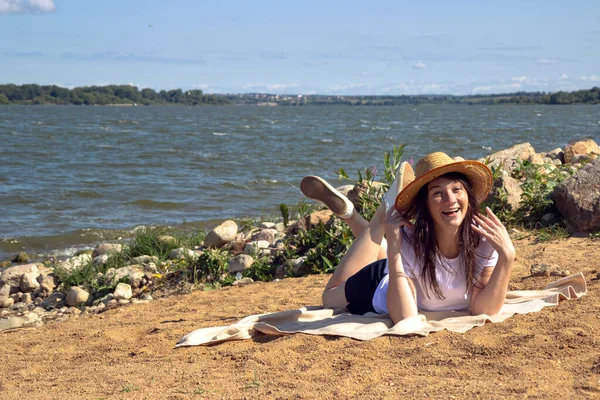 Temiz hava soluyan rahat bir kadının yan görüntüsü, parlak sıcak güneşin altında kumun üzerinde uzanan deniz ve gökyüzü ile fotokopi alanı ile birlikte.