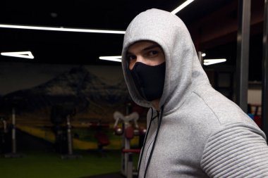Korunaklı yüz maskesi takan genç atletik bir adam koronavirüs salgını sırasında spor eğitiminde..