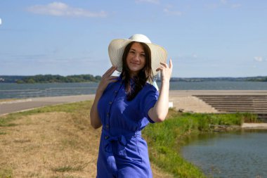 İskelede saman şapkalı, zarif elbiseli genç bir kadın harika bir manzaranın tadını çıkarıyor..