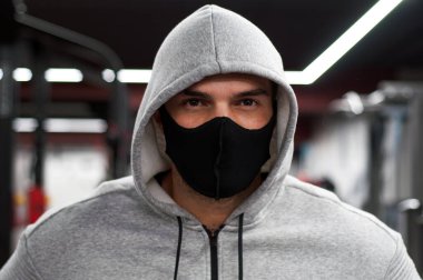 Korunaklı yüz maskesi takan genç atletik bir adam koronavirüs salgını sırasında spor eğitiminde..