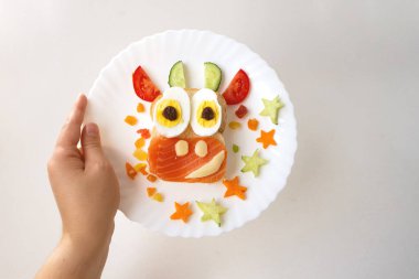 Kızarmış ekmek, kırmızı balık, peynir, kuru üzüm, yumurta ve sebzeden yapılmış yenilebilir 2021 boğa ineği sembollü komik sandviç. Çocuklar için kahvaltı fikri. Noel yemeği üst görünümü. yemek sanatı