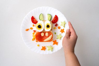 Kızarmış ekmek, kırmızı balık, peynir, kuru üzüm, yumurta ve sebzeden yapılmış yenilebilir 2021 boğa ineği sembollü komik sandviç. Çocuklar için kahvaltı fikri. Noel yemeği üst görünümü. yemek sanatı