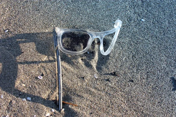 crooked and ruined sports sunglasses left on a beach in the sun