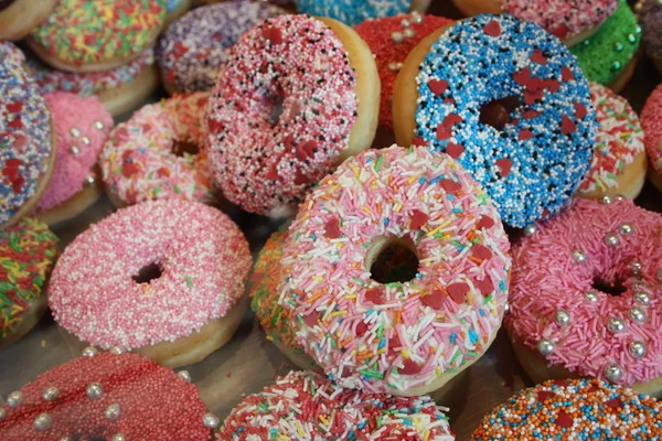 So viele Donuts mit Zuckerguss und buntem Zucker bedeckt — Stockfoto