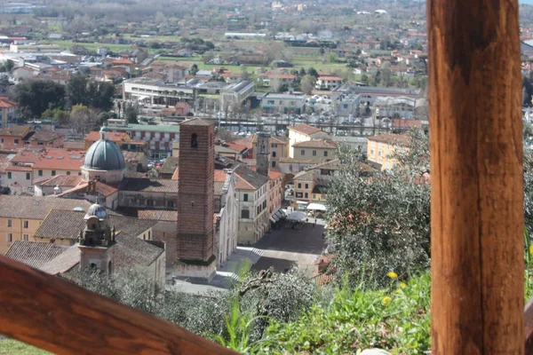 Červené střechy obydlených domů, kostel a zvonice katedrály Pietrasanta vidět ze zeleně kopce na vrcholu — Stock fotografie