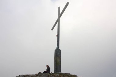 seçici odak. odak dışında. büyük bir çelik çapraz altında kalın ve yoğun sisin içinde oturan kız