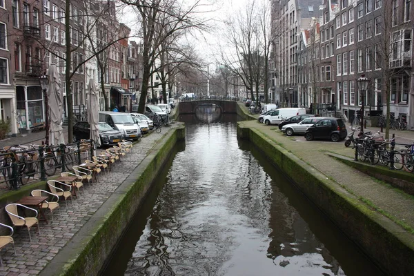 Escena de primavera temprana en la ciudad de Amsterdam. Tours en barco por los famosos canales holandeses. Paisaje urbano con casas de canal en Holanda, Países Bajos — Foto de Stock