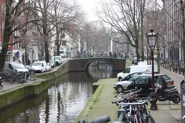 Escena de primavera temprana en la ciudad de Amsterdam. Tours en barco por los famosos canales holandeses. Paisaje urbano con casas de canal en Holanda, Países Bajos — Foto de Stock