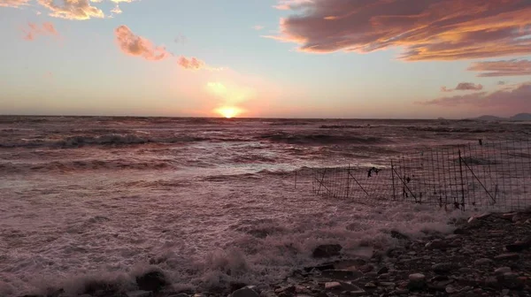 Un aperçu de la plage au coucher du soleil, un moment magique où tout est coloré avec des couleurs vives. les nuages encadrent le paysage maritime et le soleil disparaît lentement à l'horizon — Photo