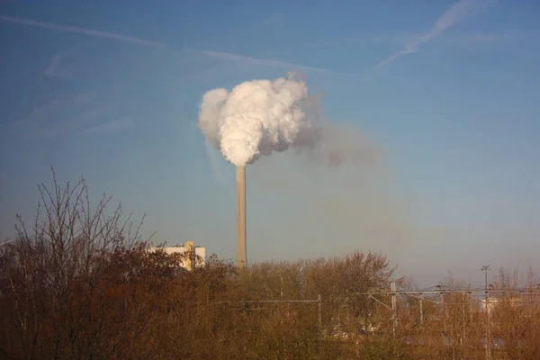 outlet of a chimney that dumps the remains of industrial processing into the clear blue sky, polluting our beautiful planet