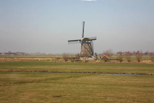 Samotny wiatrak w okolicach prowincji, czystym i zielonym z Holandii. niebo z trochę mgły i dziewiczy zielone łąki — Zdjęcie stockowe