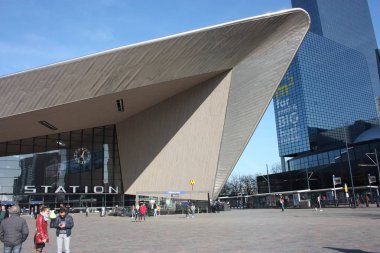 Güzel güneşli bir gün Hollanda 'ya bir gezi. Mavi gökyüzü ve geometrik yapılar ve uzun binalar hayran Rotterdam Merkez Istasyonu meydanında yürümek