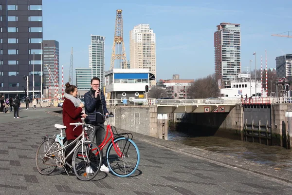 Junges verliebtes Paar, das an einem Herbsttag mit dem Fahrrad in Rotterdam unterwegs ist. Besuch des Hafens und des Flusses vor der Erasmusbrücke in Rotterdam — Stockfoto