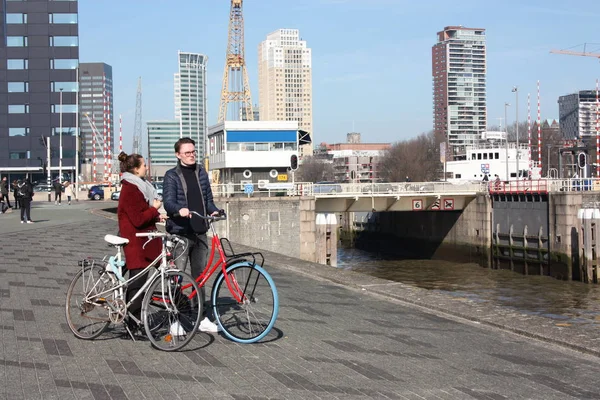 Junges verliebtes Paar, das an einem Herbsttag mit dem Fahrrad in Rotterdam unterwegs ist. Besuch des Hafens und des Flusses vor der Erasmusbrücke in Rotterdam — Stockfoto