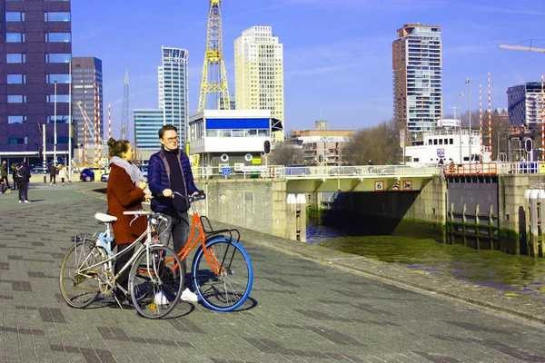 Junges verliebtes Paar, das an einem Herbsttag mit dem Fahrrad in Rotterdam unterwegs ist. Besuch des Hafens und des Flusses vor der Erasmusbrücke in Rotterdam — Stockfoto