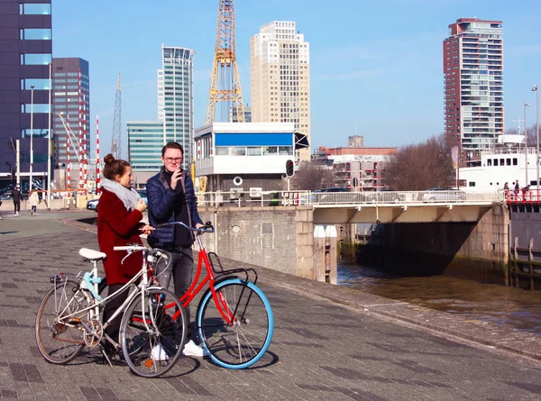 Junges verliebtes Paar, das an einem Herbsttag mit dem Fahrrad in Rotterdam unterwegs ist. Besuch des Hafens und des Flusses vor der Erasmusbrücke in Rotterdam — Stockfoto