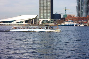 amsterdam merkez istasyonu önünde kanal veya nehir, banliyö ve turistler için toplu taşıma olarak kullanılan