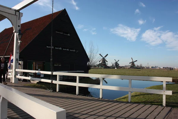 ザンセ・シャンへの春の旅。穏やかな水路、静かな川が丘の間を流れます。オランダの風車は、何世紀も後に伝統的な観光のランドマークとして立っています — ストック写真
