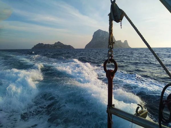 Es Vedra 'nın kayalık adası gökyüzü ve mavi deniz arasında ve İbiza' nın sisli sularında beyaz köpük