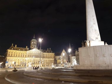 Hollanda 'daki sis binaları ve ışıkların ortasında Amsterdam' daki Baraj Meydanı