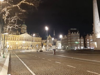 Hollanda 'daki sis binaları ve ışıkların ortasında Amsterdam' daki Baraj Meydanı