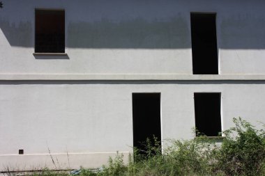 Terk edilmiş ve yenilenmeye ihtiyacı olan beyaz bir evin ön cephesi için kayıp pencere ve kapı.