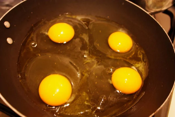 四个鸡蛋在一个圆形的黑锅中煮熟 — 图库照片