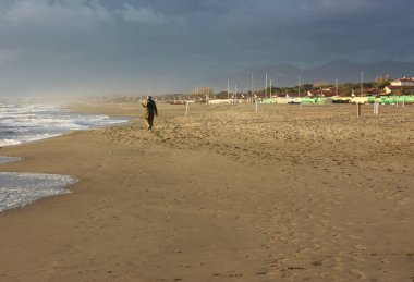 İtalyan kışının güneşli bir gününde Versilia 'nın kumlu kumlu sahilinde dinlendirici yürüyüşler.