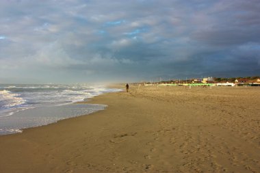 İtalyan kışının güneşli bir gününde Versilia 'nın kumlu kumlu sahilinde dinlendirici yürüyüşler.