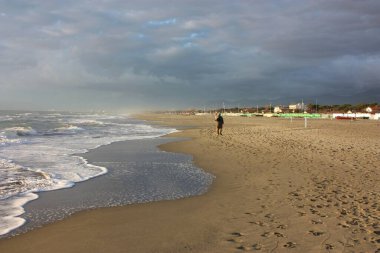 İtalyan kışının güneşli bir gününde Versilia 'nın kumlu kumlu sahilinde dinlendirici yürüyüşler.
