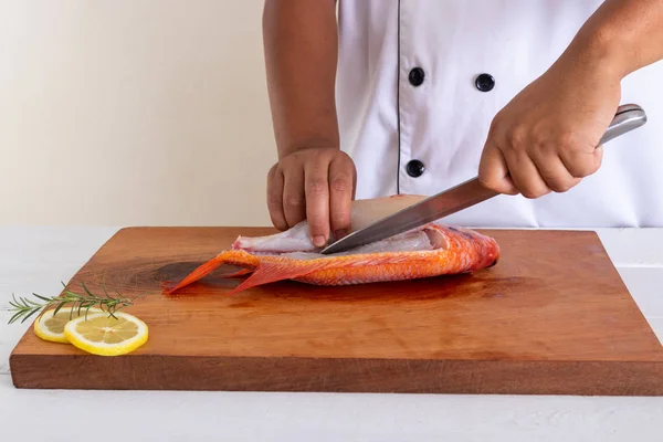 Chef cutting fish in the kitchen.