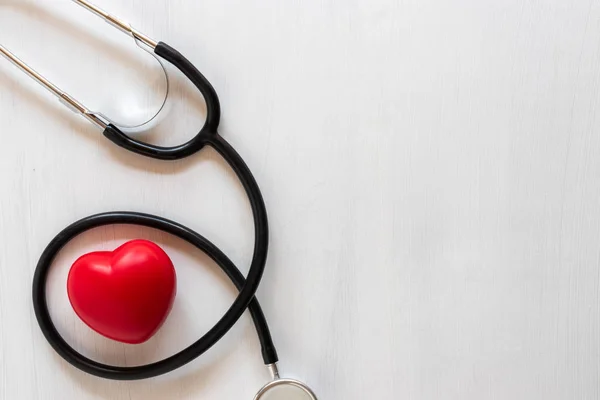 Stethoscope and heart on wooden background. Health care concept