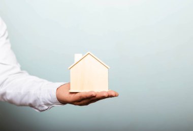 Genç adam elinde oyuncak ev tutuyor. Ev sigortası konsepti.