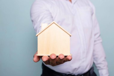 Genç adam elinde oyuncak ev tutuyor. Ev sigortası konsepti.