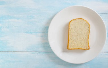 Mavi ahşap arka plan üzerinde beyaz tabak taze sağlıklı ekmek en iyi görünümü.