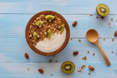 Beyaz ahşap masa üzerinde üstten görünüm bir ahşap kase ve nane ile kaşık yoğurt. Sağlık gıda kavramı.