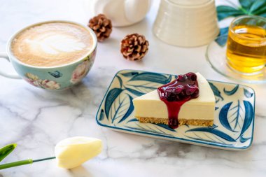 Beyaz çanak ve kahve latte sanat üzerine ev yapımı Blueberry cheesecake.