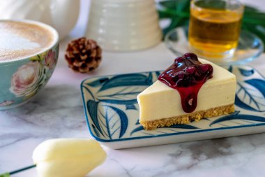 Beyaz çanak ve kahve latte sanat üzerine ev yapımı Blueberry cheesecake.