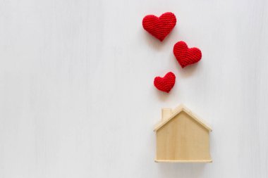 Beyaz arka plan üzerinde kırmızı iplikten yapılmış Kalp ile ev tasarrufu. Ev sigortası kavramı.