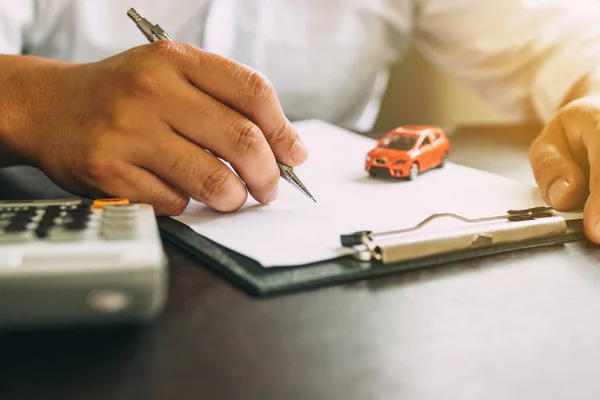 Businessman with car insurance contract and calculator.