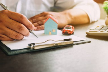 Araba ve ev sigortası sözleşmesi ve hesap makinesi ile işadamı.