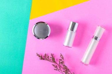 Renk arka planda beyaz kozmetik şişe kapları üst görünümü.