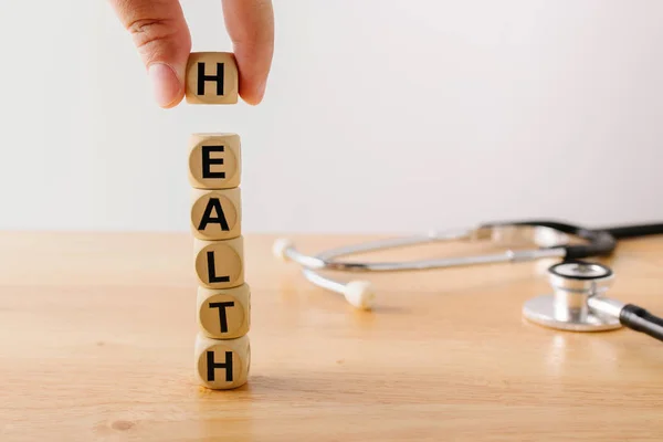 Cube block wood with word health and stethoscope on wooden background. Health insurance concept.