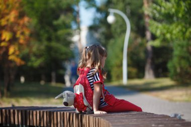Yaz aylarında parktaki bir bankta oturan bir sırt çantası ile yalnız küçük kız