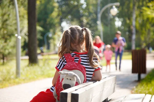 Yaz aylarında parktaki bir bankta oturan bir sırt çantası ile yalnız küçük kız